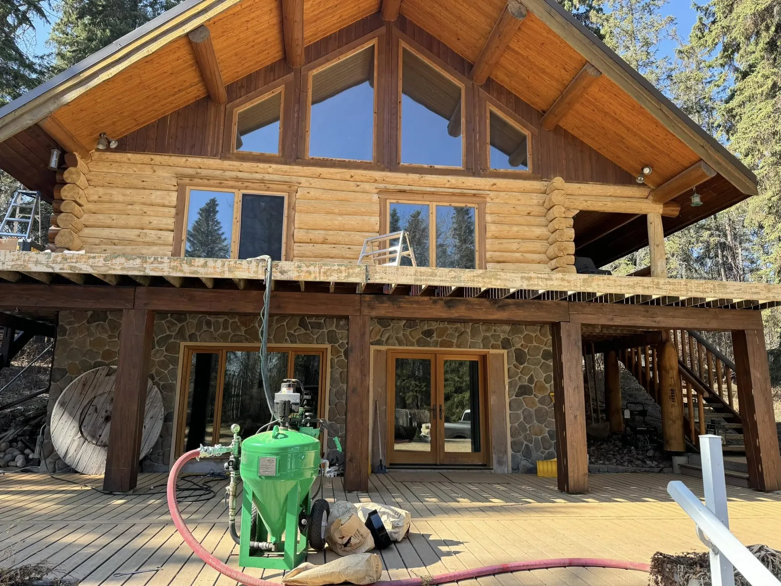 Alberta log home freshly stripped to bare wood, Evolve's mobile blasting rig on the deck
