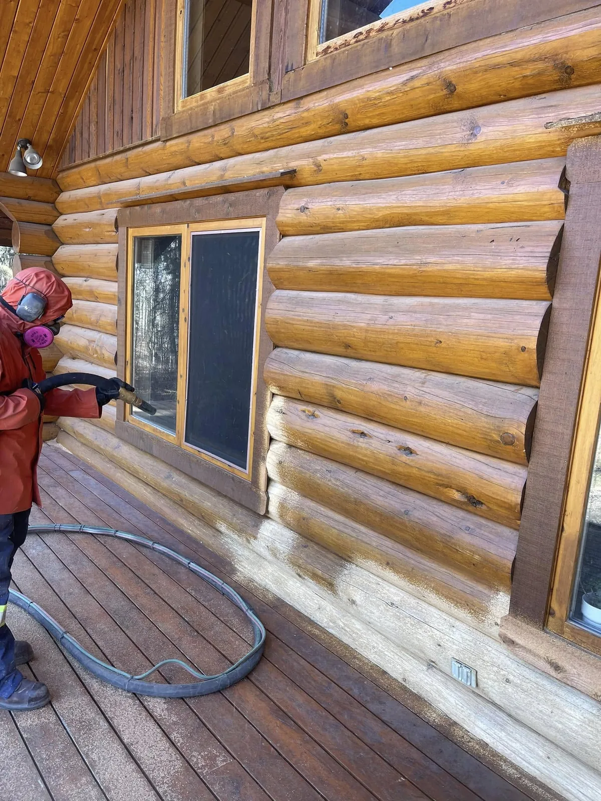 Evolve crew member applying new stain to the freshly stripped log wall